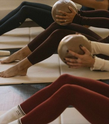 Holding a ball between the legs on a mat